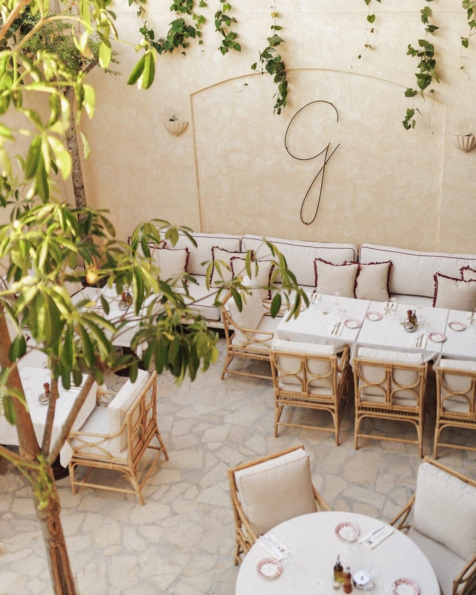 The courtyard from above, white tables under the trees and the G on the wall