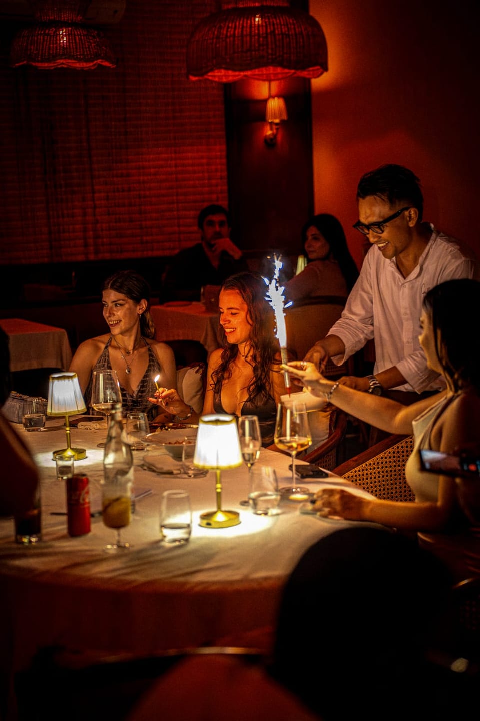 A table of guests at night under small table lamps